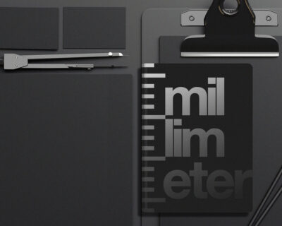 Schwarzes Schreibwarenset mit Notizbuch, Clipboard, Stift und Lineal, auf Notizbuch mit 'millimeter'-Schriftzug und Maßstabsdesign