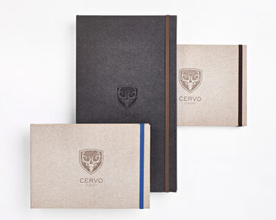 Drei Notizbücher mit geprägtem CERVO-Logo in Schwarz, Beige und Grau, gestaffelt angeordnet