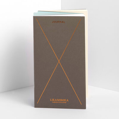 Brown 'LIKA MIMIKA' notebook with orange cross lines and the inscription 'Handcrafted in Japan'