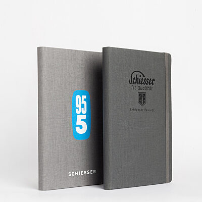 Zwei graue Schiesser-Notizbücher mit blauen und schwarzen Logos